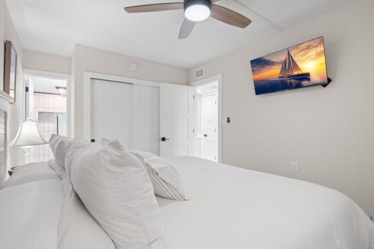 Master bedroom with wall-mounted smart TV closet and en-suite bathroom in Fifty Gulfside Unit 107