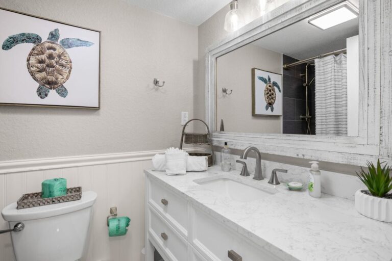 Remodeled guest bathroom with marble vanity and sea turtle artwork in Indian Rocks Beach rental