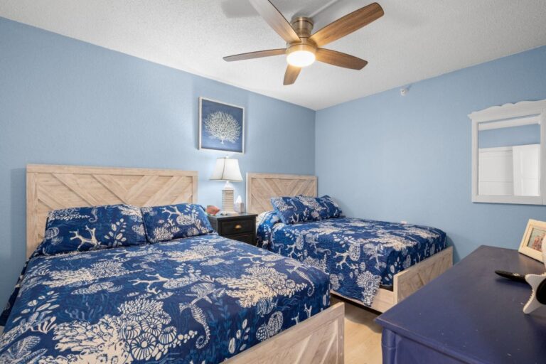 Blue themed guest bedroom with two full beds and coastal bedding at Fifty Gulfside condo Unit 107