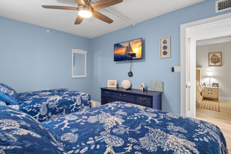 Guest bedroom with wall-mounted smart TV and blue coastal decor in Indian Rocks Beach vacation condo
