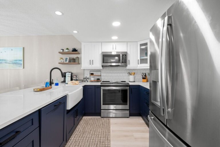 Newly remodeled kitchen with navy blue cabinets stainless steel appliances and hexagon backsplash in Florida beach condo