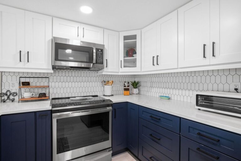 Modern kitchen with stainless steel stove microwave and white hexagon tile backsplash in Indian Rocks Beach rental